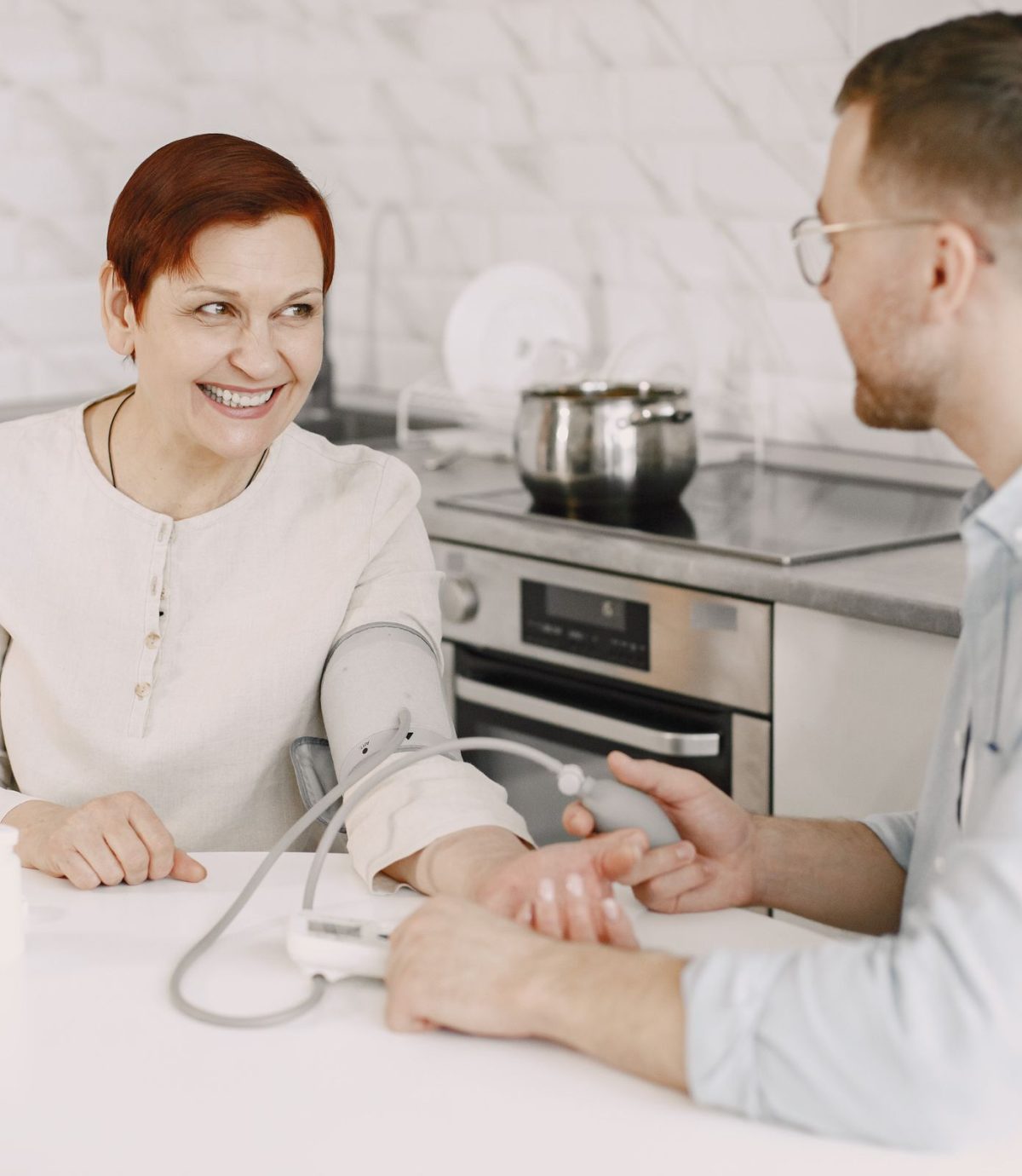 Pflegekraft im warmen Gespräch mit einem Senior im Wohnzimmer